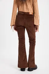 Pantalon de pana color marrón, de corte ajustado con costuras verticales frontales y tajos en el ruedo.