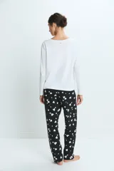 Pijama compuesto por una remera de manga larga blanca y un pantalón negro con estampado de corazones blancos. El pantalón cuenta con cintura elástica para mayor comodidad.