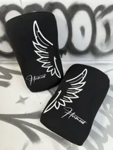 Par de rodilleras negras de neopreno de 7mm con logo de alas y nombre de la marca en color celeste.