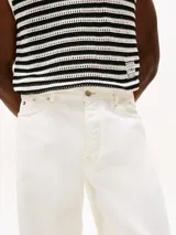 Pantalón jean blanco de corte amplio y pierna recta, con cintura ajustable en la parte trasera. Presenta cierre de cremallera con botón, dos bolsillos delanteros de parche y dos bolsillos traseros ribeteados. Detalles distintivos de la colección APXGP.