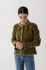 Saco de punto color beige, con diseño de calados en la parte superior y mangas, cierre frontal con botones y cuello redondo.