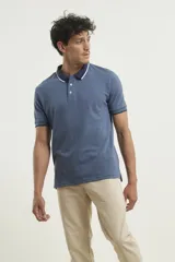 Chomba de piqué azul con cuello clásico, mangas cortas y corte recto. El cuello y los puños tienen detalles a contratono en azul marino y blanco.