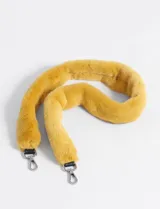 Asa de reemplazo para cartera, confeccionada en pelo sintético color mostaza/amarillo. Cuenta con ganchos metálicos plateados en ambos extremos para sujetar a la cartera.