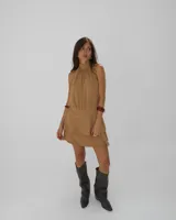 Vestido corto color tostado con cuello alto tipo halter y falda con volados superpuestos.