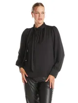 Blusa negra de acabado satinado con cuello alto fruncido, detalle de lazo para anudar y cierre lateral con botones. Presenta mangas largas estilo balloon con puños ajustados.
