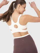 Conjunto deportivo compuesto por un top de entrenamiento color crema con diseño cruzado en la parte inferior y un short biker color marrón con cintura cruzada en contraste.