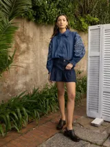 Camisa celeste de denim con bordado de hojas en las mangas, cuello con volados y botones de flor.