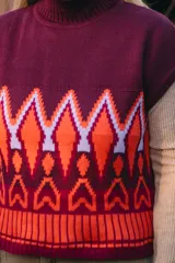 Chaleco de punto color borgoña, naranja y blanco con cuello alto y patrón geométrico. Confeccionado en lana y acrílico.