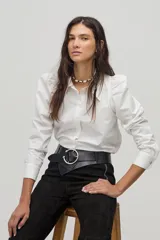 Camisa blanca de popelina de algodón con cuello camisero clásico, hombros abullonados, mangas largas y botones de nácar en el frente.