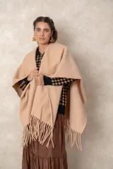Ruana abierta de color beige, confeccionada en tejido de punto con terminación de flecos en el ruedo.