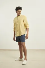 Camisa de cuello mao y manga larga, confeccionada en una mezcla de lino y algodón. Presenta un diseño de corte recto con botones en tono natural y un bolsillo pequeño en el pecho.