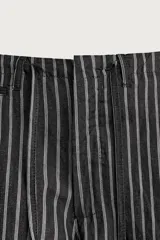 Pantalón relaxed fit de mezclilla con mezcla de algodón y lino, con diseño de rayas verticales oscuras y claras. Cuenta con cintura ajustable con cordón, bolsillos frontales, bolsillo cerillero y cierre frontal con cremallera y gancho metálico.