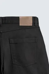Pantalón relaxed fit negro confeccionado en tejido de algodón con estructura diagonal, estilo de cinco bolsillos y cierre frontal con cremallera y botón metálico.