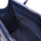 Cartera grande tipo tote bag de textura denim con detalles en cuero sintético azul oscuro. Cuenta con doble asa de mano, correa ajustable para el hombro y un bolsillo frontal con cierre y el logo de la marca Extra Large.