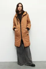 Campera de nylon larga oversized color negro, con capucha, tres bolsillos externos y uno interno. De tela capitoneada, con puños en las mangas y forro polar.