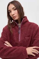 Buzo de sherpa con textura capitoneada, color bordó, con cuello alto y cierre frontal parcial. Presenta bolsillos laterales y calce relajado.