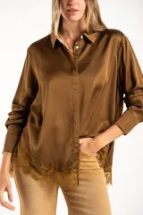 Camisa de satén color arena, de corte clásico con cuello camisero, manga larga con puños abotonados y detalle de encaje en el ruedo.