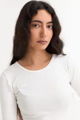 Remera de manga larga con cuello redondo a la base, confeccionada en algodón suave de corte ajustado.