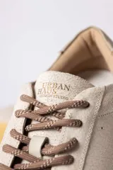 Championes urbanos de gamuza color marrón, con suela de goma en tono crema y cordones jaspeados. Presenta un refuerzo en la puntera y un detalle en cuero beige en el talón.