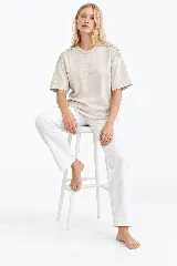 Remera oversize de algodón con acabado stonewash, color gris azulado, manga corta y cuello redondo. Cuenta con apliques bordados a mano en forma de hojas con canutillos plateados sobre los hombros.