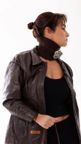 Cuello tejido a mano en lana merino, de color marrón chocolate, con detalle de flor tejida en color gris.