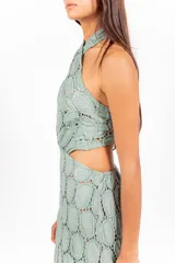 Vestido largo de encaje con patrón circular, color lila, de corte halter con tiras cruzadas al cuello y aberturas laterales en la cintura.