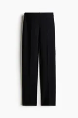 Leggings negros de punto pesado de corte sastre, con elástico oculto en la cintura, bolsillos decorativos en la parte trasera, pliegues cosidos al frente y pequeñas aberturas en los bajos.