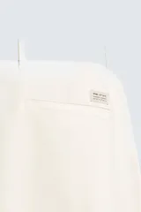 Pantalón chino de corte ajustado, color beige, con bolsillos laterales y bolsillos traseros de vivo. Cuenta con cierre frontal de cremallera y botón.