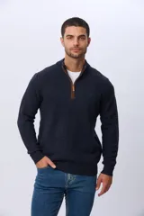 Buzo tejido de punto con textura en relieve, color azul marino. Presenta cuello alto con cierre frontal parcial y detalles en gamuza en la zona del cierre. Posee puños y ruedo acanalados.