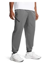 Pantalón de jogging Under Armour modelo Unstoppable Wvn de color gris, con bolsillos laterales con cierre y diseño deportivo.