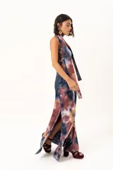 Vestido largo de corte recto y escote strapless, con estampado estilo batik en tonos azul, naranja y bordó. Incluye una bufanda larga integrada al diseño que cae desde el cuello.
