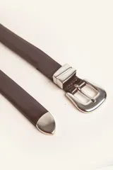 Cinturón de cuero liso color marrón oscuro con hebilla plateada y pasador metálico decorativo.