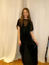 Vestido largo sin mangas con escote en V halter y aberturas laterales (cut-outs) en la cintura. El cuerpo superior presenta un llamativo diseño estampado multicolor, mientras que la falda larga es de tejido texturizado brillante en color verde esmeralda con inserciones godet en el ruedo.