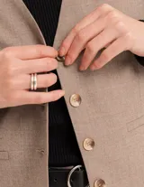 Chaleco de vestir gris oscuro con textura tipo tweed, escote en V y botones frontales. Corte levemente entallado y largo a la cintura.