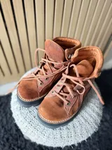 Botas Saura de cuero y gamuza en color tostado, con cordones frontales, suela gruesa y diseño tipo borceguí.
