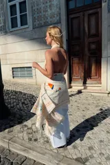 Top negro sin mangas con cuello halter drapeado y cierre posterior con botón.