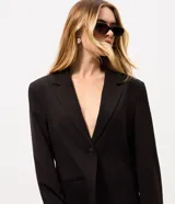 Blazer de sastrería negro de corte oversize, con solapas clásicas, cierre frontal de un botón y bolsillos con solapa.