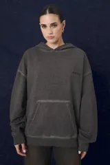 Buzo hoodie de corte oversize en color gris con efecto desgastado, cuenta con capucha, bolsillo frontal tipo canguro y logo bordado en el pecho.