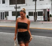 Short pollera negro de tiro medio con capa superpuesta translúcida de malla fina, decorada con delicados bordados de lentejuelas y abalorios con motivos florales.