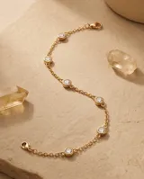 Pulsera de acero con baño de oro y dijes circulares con circonias engastadas.