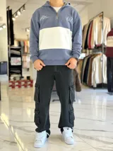 Hoodie de felpa con capucha y medio cierre frontal, diseño en bloques de color celeste y blanco, con bordados decorativos en el pecho.