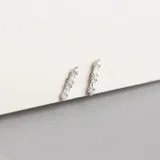 Par de aros largos plateados con forma lineal, con tres brillantes redondos y dos rectangulares.