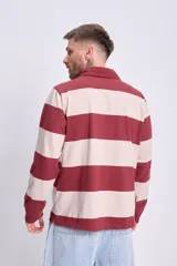 Remera tipo rugby de manga larga a rayas horizontales color bordó y beige, con cuello polo y cierre de dos botones. Estampa frontal con la leyenda "Race Team".