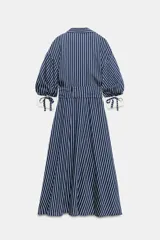 Vestido midi azul marino con rayas blancas, cuello solapa, escote en V y cierre frontal con botones. Cuenta con mangas abullonadas por debajo del codo con puños anchos a contraste, cinturón ajustable del mismo tejido con hebilla metálica y falda evasé.