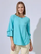 Blusa celeste de tejido piqué con mangas 3/4 y volados en los puños.