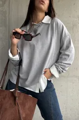 Sweater de punto color gris, de corte holgado y diseño de manga larga con costuras visibles en los hombros. Presenta cuello redondo y puños acanalados.
