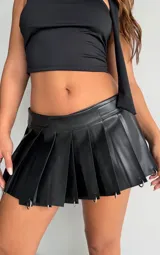 Minifalda plisada de efecto cuero color negro, con diseño de tablas marcadas y apliques de argollas metálicas en el ruedo. Cuenta con cintura ajustable mediante cierre de velcro.