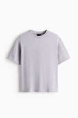 Remera de algodón pesado color lila, de corte holgado, con cuello redondo ribeteado, hombros caídos y mangas cortas.