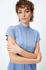 Top blanco de tejido de punto acanalado, con cuello alto, mangas cortas y abertura central en el ruedo.