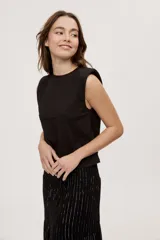 Remera sin mangas negra con cuello redondo y hombros estructurados con hombreras, de corte recto y largo a la cintura.